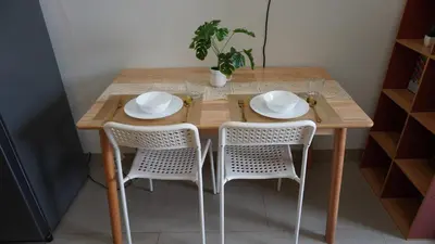 a wooden table with two chairs and a table with plates at Shore 2 Residences in Manila