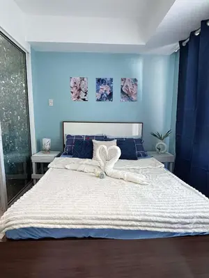 a bedroom with a large white bed with blue walls at The Session Azure in Manila