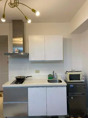 a kitchen with white cabinets and a sink and a microwave at Azure Staycation in Manila