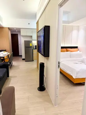 a hotel room with a bed and a flat screen tv at Venice Luxe Cozy 1 BedRoom, Pool, Netflix, Kitchen, Canal Mall Access in Manila