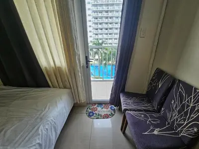 a bedroom with a bed and a chair and a window at Shell Low Floor Amenity Pool View with Balcony MOA Shell004 in Manila