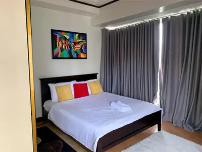a bedroom with a bed with white sheets and colorful pillows at 2 Bedroom at The infinity Condominium at BGC in Manila