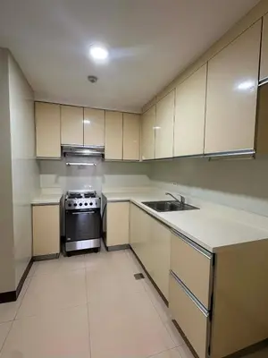 a kitchen with white cabinets and a stove and a sink at 2 Bedroom at The infinity Condominium at BGC in Manila