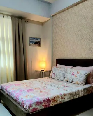 a bedroom with a bed with a floral bedspread at House of B&Y 101 newport blvd across treminal3 in Manila