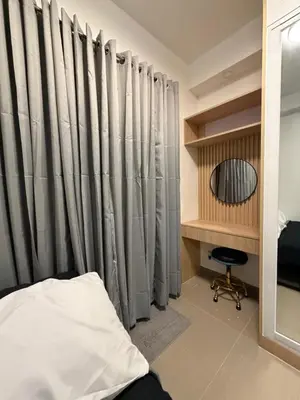 a bedroom with curtains and a mirror and a chair at Premium Studio at Shore Residences in Sampong