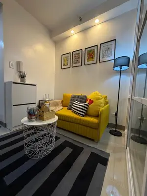 a living room with a yellow couch and a table at Premium Studio at Shore Residences in Sampong