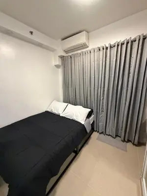 a small bedroom with a black bed and curtains at Premium Studio at Shore Residences in Sampong