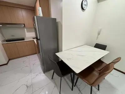 a kitchen with a table and chairs and a refrigerator at Sunnyplace Residences 2 BR Near NAIA Airport in Manila