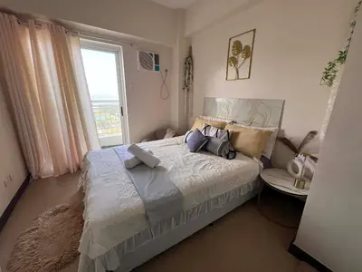 a bedroom with a large bed with a window at Casa Feliz Staycation in Manila