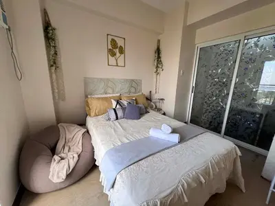 a bedroom with a large bed with a large window at Casa Feliz Staycation in Manila