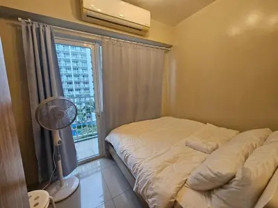 a bedroom with a bed and a window with a fan at Amenity Pool View 1 BR balcony MOA SMX Ikea Shore002 in Manila