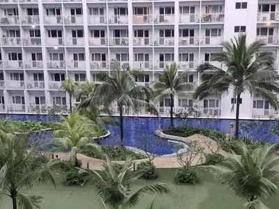 a large white building with palm trees in front of it at Amenity Pool View 1 BR balcony MOA SMX Ikea Shore002 in Manila
