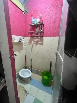 a small bathroom with a toilet and a green bucket at Liza residence in Manila