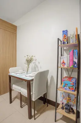 a dining room table with two chairs and a book shelf at Cozy 1BR Balcony with Pool View Plus Free Parking in Manila