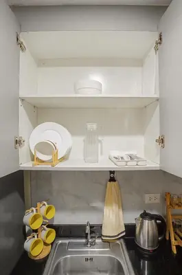 a kitchen sink with plates and utensils on a shelf at Cozy 1BR Balcony with Pool View Plus Free Parking in Manila