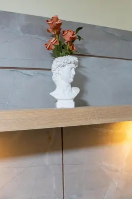 a statue of a bust sitting on a shelf with flowers at Cozy 1BR Balcony with Pool View Plus Free Parking in Manila