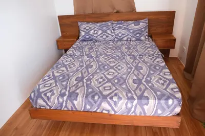 a bed with a wooden headboard and a blanket on it at Idesia Dasmarinas NEW 3BR home with wifi & parking in Dasmariñas
