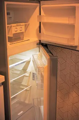 an empty refrigerator with its door open with its door at Cozy Tahanan Azure Studio close to NAIA in Manila