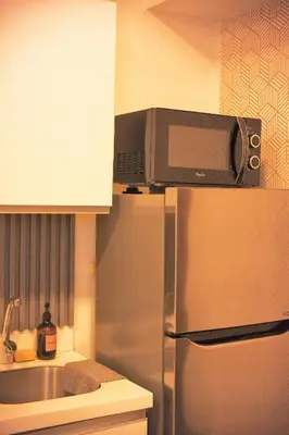 a microwave on top of a refrigerator in a kitchen at Cozy Tahanan Azure Studio close to NAIA in Manila