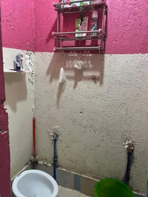 a bathroom with a toilet and a green bucket at Liza homestay in Manila