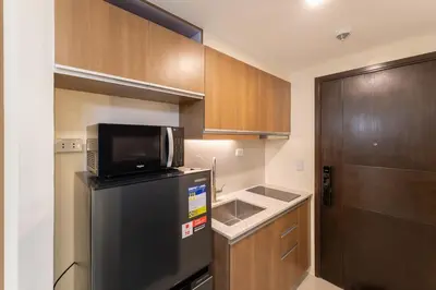 a small kitchen with a refrigerator and a microwave at Modern Condo at Park McKinley West with Wi-Fi and Washer in Manila