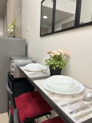 a table with plates and a vase with flowers on it at Chic Urban Escape at S Residence Tower 3 in Manila