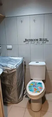 a bathroom with a toilet and a trash can at JandG MOA Staycation Amenity view at Shell residence in Manila