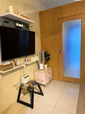 a living room with a tv and a glass table at Dusk Suites elevated escapes at Shell Residences, Mall of Asia Complex in Manila