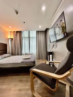a bedroom with a bed and a chair and a tv at Prime Makati Condo Near Poblacion & Malls in Manila