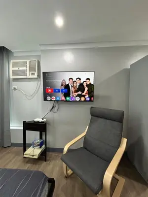 a living room with a tv and a chair at Prime Makati Condo Near Poblacion & Malls in Manila