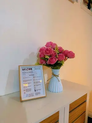 a vase of pink roses sitting on a table with a sign at The Warm Suite By ANC at Azure in Manila