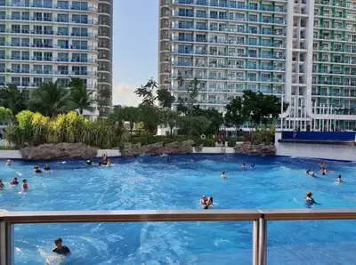 a group of people in a swimming pool with buildings at The Warm Suite By ANC at Azure in Manila