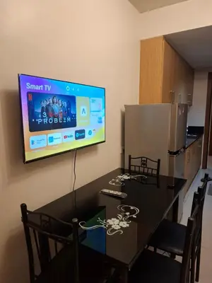 a dining room with a table and a tv on the wall at Shell MOA Facing View 1BR near Ikea, NAIA, PICC Shell003 in Manila
