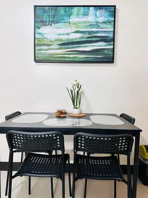 a table with two chairs and a painting on the wall at Minimalist 1BR Condo at Araneta City, Cubao in Manila