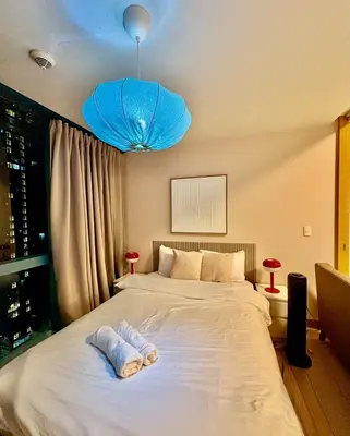 a bedroom with a large white bed with a blue light at 1BR at One Uptown Residence BGC Across Uptown Mall in Manila