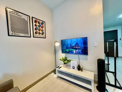 a living room with a tv on a wall at 1BR at One Uptown Residence BGC Across Uptown Mall in Manila