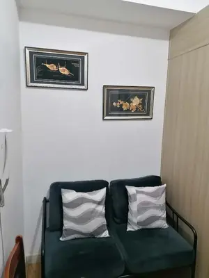 a green couch in a room with two pictures on the wall at Aureascondo in Manila