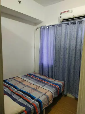 a small bed in a room with a blue curtain at Aureascondo in Manila