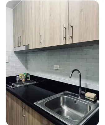 a kitchen with a stainless steel sink and wooden cabinets at Staycay at SRESIDENCES in Manila