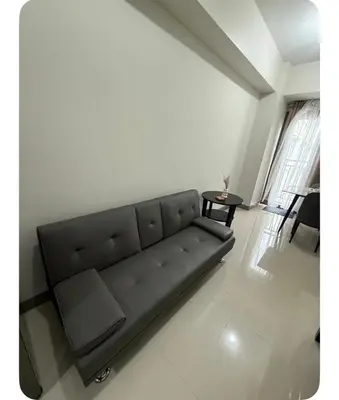 a black couch in a living room with a table at Staycay at SRESIDENCES in Manila