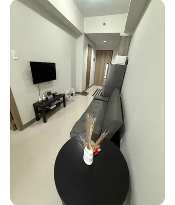 a living room with a black table and a tv at Staycay at SRESIDENCES in Manila