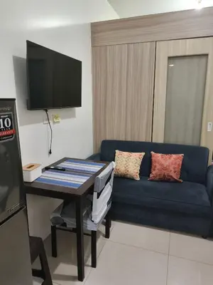 a living room with a blue couch and a tv at Shore Recidences Mall Of Asia Cullen in Manila