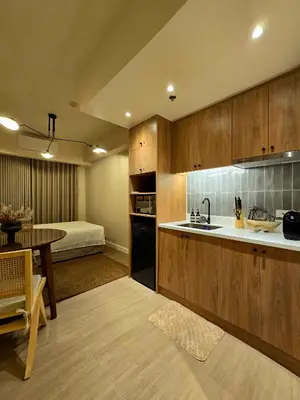 a kitchen with a sink and a table and a bed at The Florentine Suite in Manila