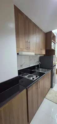 a kitchen with wooden cabinets and a black counter top at The Shore 3 Chic Suite in Manila