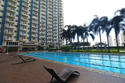 a swimming pool with chairs in front of a large building at Comfy 1BR Self Check-In at Light Residences in Manila