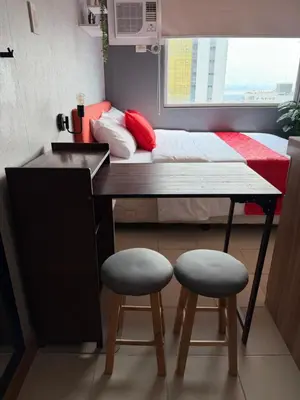 a small room with a bed and two stools at PaulBert's Cabins III in Manila