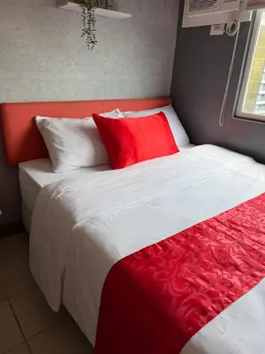 a bedroom with a large bed with red and white pillows at PaulBert's Cabins III in Manila