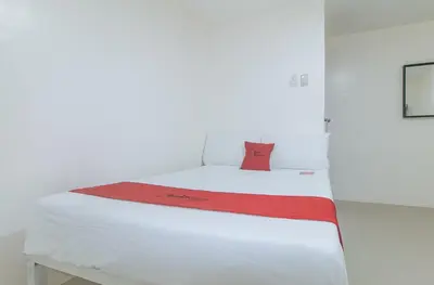 a bed in a room with a red pillow on it at RedDoorz at FCCG GoldMoon Boutique Hotel in Manila