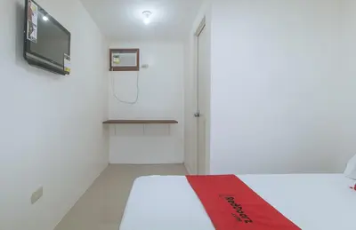 a room with a shower and a bed with a red blanket at RedDoorz at FCCG GoldMoon Boutique Hotel in Manila