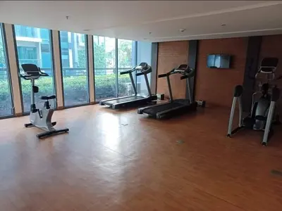 a gym with several tread machines in a room with windows at Eighty One Newport Blvd Condo near NAIA3 in Manila